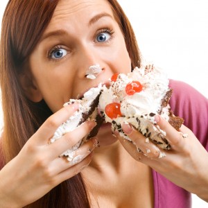 Cheerful woman eating pie, over white